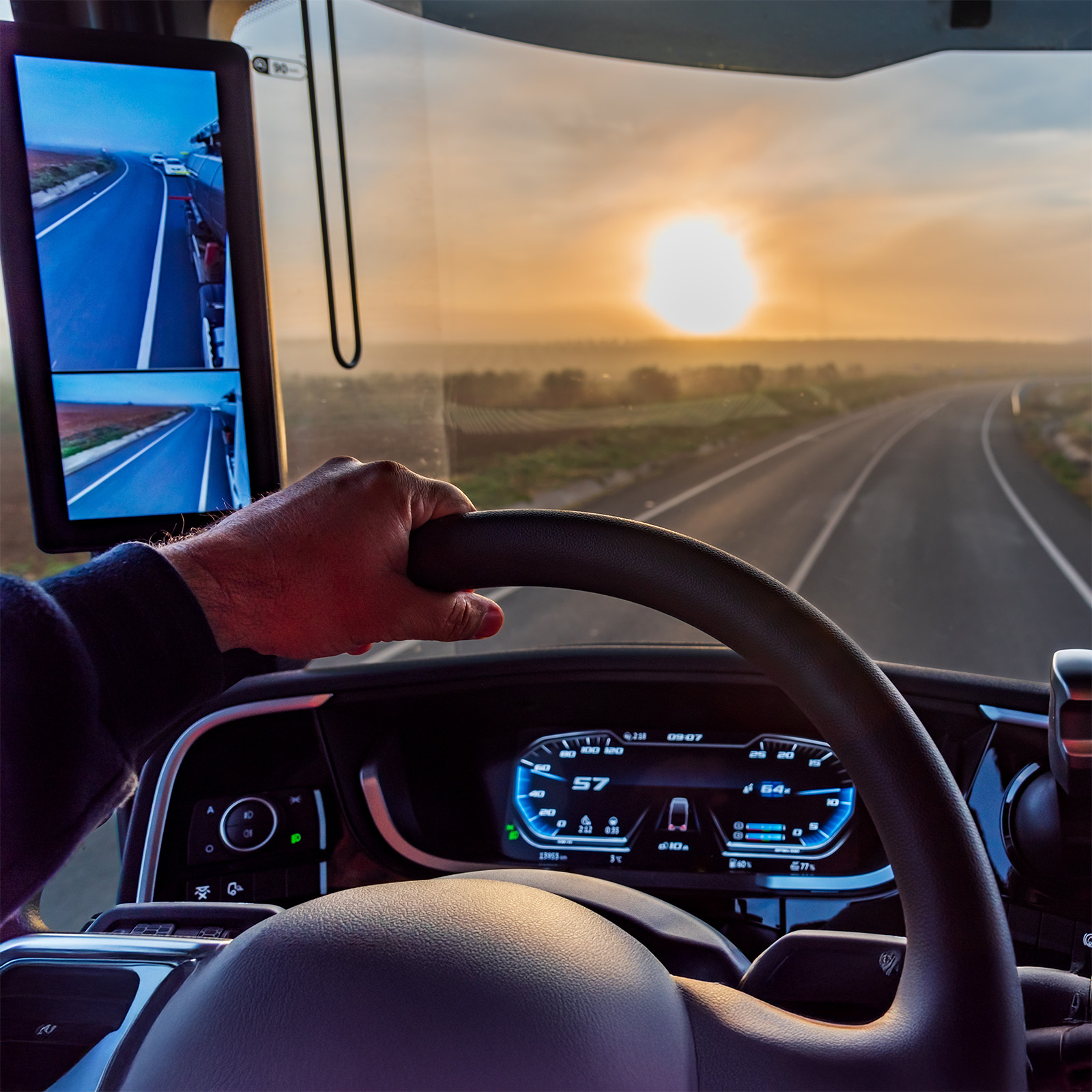 Hand am Lenkrad bei einer sicheren Fahrt mit Catrici Transporte im LKW dem Sonnenaufgang entgegen.